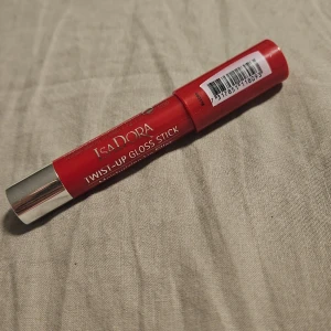 Isadora Twist-Up Gloss Stick röd - Snygg röd Twist-Up Gloss Stick från Isadora med silvrig detalj på korken. Ger glansiga och återfuktade läppar med en intensiv färg. Enkel att applicera tack vare den smidiga pennformen. Perfekt för dig som vill ha färg och glans i ett.