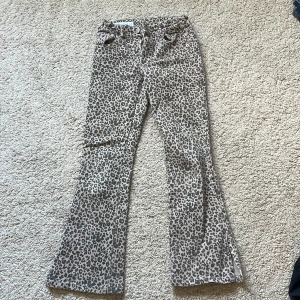 Leopardmönstrade jeans  från Zara - Säljer ett par coola leopardmönstrade jeans  från Zara i beige och grå toner. Kjolen har slits nertill och klassisk jeanslook med fickor både fram och bak. Perfekt för dig som vill sticka ut med ett djuriskt mönster.