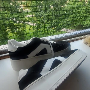 Svarta och vita sneakers med mockadetaljer - Snygga sneakers från Cellini i svart och vitt med coola kontrastpaneler och vit sula. Ovandelen är i mocka och syntet, med vita snören och rund tå. Perfekta för dig som gillar en stilren men sportig look.