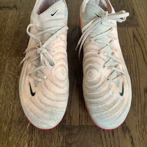 Nike Phantom GX II Elite fotbollsskor rosa - Nike Phantom GX II Elite AG-PRO, fotbollsskor i rosa med svarta detaljer. Sulan är rosa med dobbar speciellt utformade för konstgräsplaner. 