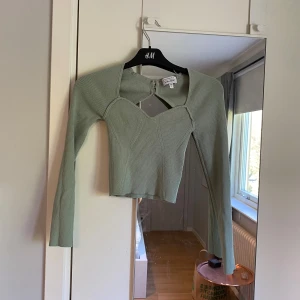 Grön ribbad topp från & Other Stories - Säljer en stilren grön ribbad topp från & Other Stories. Toppen har en unik design med öppen rygg och långa ärmar. Den är aldrig använda men prislappen är tyvärr borta 💚