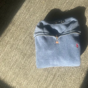 Ralph lauren quarter zip-blå-M - Beskrivning: Säljer en snygg och bekväm 1/4 zip tröja från Ralph Lauren i storlek Medium. Tröjan är i en stilren blå färg med den klassiska röda Polo-loggan broderad på bröstet. Perfekt för både vardag och lite mer uppklädda tillfällen.  Skick: Bra skick, inga större tecken på slitage.  Storlek: Medium  Material: Mjuk och skön bomullsblandning.  Frakt & betalning: Kan skickas eller mötas upp enligt överenskommelse.  Skicka gärna ett meddelande om du har 