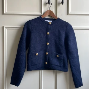 Mörkblå cardigan jacka med guldknappar från Zara - Säljer en stilren mörkblå cardigan jacka/kofta från Zara, strl S med guldknappar. Endast använd fåtal gånger. Koftan har en rund halsringning och två snygga fickor framtill. Perfekt för en elegant look nu till sommaren och våren❣️