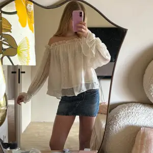 Säljer en söt vit offshoulder blus med prickigt mönster. Blusen har långa ärmar och en luftig passform, perfekt för en somrig look. Den är gjord i ett lätt och bekvämt material. Den är från Gina Tricot. 