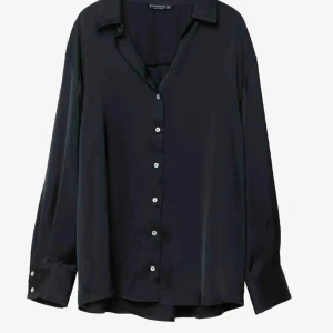 Svart blus från Stradivarius - Elegant svart blus från Stradivarius med klassisk krage och knappar framtill. Blusen har långa ärmar och är perfekt för en stilren look. Tillverkad i ett mjukt och följsamt material.