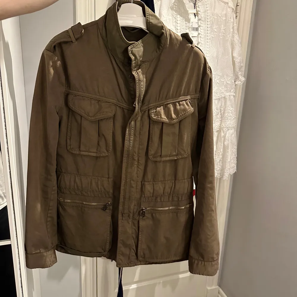 En Grön Fieldjacka från Moncler, jackan är en size 3 vilket motsvarar ungefär en M. Jackan är producerad under tidigt 2000-tal (därav brun label) och är införskaffad på Garmsmarket som garanterar äkthet. Den är inte fodrad och passar därför vår sommar bäst. Jackan är i 7/10 cond och tvättas självklart innan frakt. . Takit.