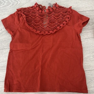 topp med spetsdetaljer från ASOS - Säljer en  topp från ASOS med vacker spetsdetalj runt halsen. Toppen har korta ärmar och är perfekt för en stilren look. Materialet är mjukt och bekvämt.