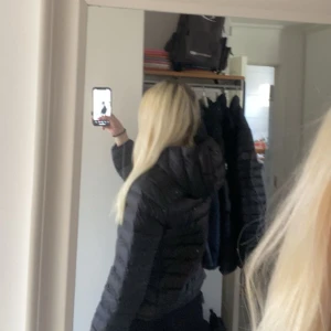 Svart dunjacka från Levi's - Säljer en svart dunjacka från Levi's med dragkedja. Jackan har en pufferdesign och är perfekt för kyligare väder. Den är tillverkad i Bangladesh och har en stilren look.