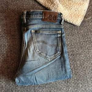 Blå jeans från Lee - Säljer ett par klassiska blå jeans från Lee. De har en normal passform med fem fickor och en snygg slitning på baksidan. Perfekta för en avslappnad stil. W31 L34