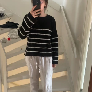 Svart och vit randig tröja - Säljer en svart tröja med vita ränder. Tröjan har en avslappnad passform och långa ärmar, perfekt för en bekväm stil. Den är enkel att matcha med olika outfits.