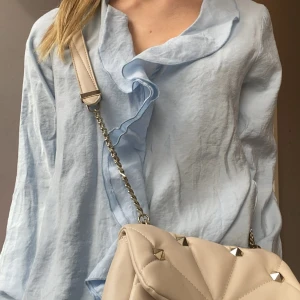 Snygg beige väska med nitar - Säljer en så snygg och trendig veige väska med guldiga nitar från Zara (gammal kollektion) Är i väldigt bra skick då den endast är använd ett fåtal gånger och säljer då den ej kommer till användning. Perfekt att piffa upp en outfit med🙌🏼