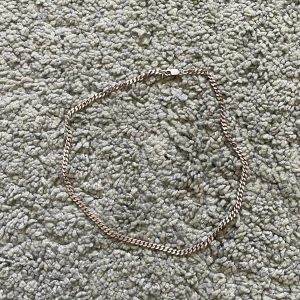 Silverfärgat halsband - Säljer ett stilrent silverfärgat halsband med klassisk kedjedesign. Perfekt för att ge en elegant touch till din outfit. Lås i metall för säker användning. 