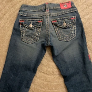 True religion jeans - Snygga blå jeans från True Religion med kontrastsömmar och dekorativa bakfickor. Jeansen har en låg midja och en slim passform som framhäver figuren. Perfekta för en avslappnad stil med en touch av detaljer. Innerben längd-87, midjemått-37 jag är 163 och de hade passat personer upp till 167.💞