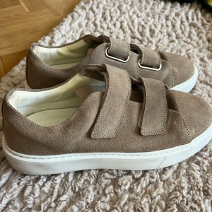 Beige sneakers med kardborreband - Snygga beige sneakers i mocka med kardborreband! Använda ca 3 gånger. Nypris 1300 kr🩷