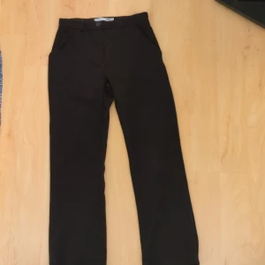 Svarta byxor med knappdetalj Lager 157 - Snygga svarta byxor med en stilren design och knappdetalj i midjan. Perfekta för en elegant look. Passar bra till både vardag och mer uppklädda tillfällen.