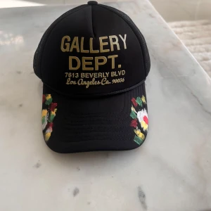 Svart keps  - Snygg svart keps. med text i guld på framsidan och färg på skärmen. Kepsen har ett nätmaterial på baksidan för ventilation och justerbar passform. Aldrig använd eftersom den inte passar mitt huvud