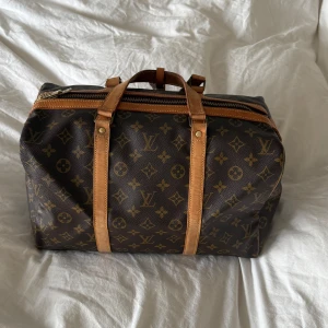 Brun monogramväska från Louis Vuitton - Säljer nu min älskade Louis Vuitton väska, modell Sac Souple 35. Väskan är köpt från Vestiaire men utan kvitto, har dock blivit äktighets kontrollerad samt varit i LV butiken.   Alla 4 guldknappar har blivit utbytta för nya  på Louis Vuitton butiken. Perfekt väska att ha som varje dag väska men funkar även utmärkt som en mindre weekend väska. Den har används flitigt men blivit väl omhändertagen och har inga synliga större defekter förutom en mindre vit fläck. Bredd 35cm, höjd 22cm, djup 20cm💕