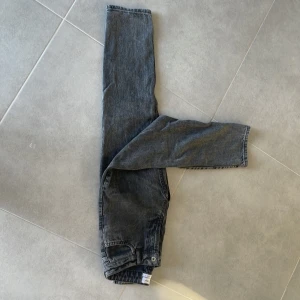 Svarta straight jeans från Grunt - Säljer ett par svarta jeans från Grunt i storlek 25. Modellen har klassisk femficksdesign, raka ben och normal passform. Jeansen är tillverkade i slitstarkt denim och har en snygg tvättad look med knapp och dragkedja framtill.