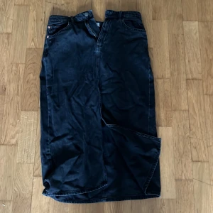 Svart jeanskjol från Lindex - Svart lång jeanskjol från Lindex ej använd med klassiska fickor fram och bak, bälteshällor och knappdetaljer i midjan. Rak modell med slits framtill för extra rörelsefrihet. Ungefär vid knäskålarna på mig och jag är 172,5 cm, tvättas och stryks innan jag skickar☺️