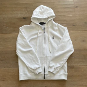 Polo Ralph lauren hoodie - Säljer denna riktigt snygga vita Ralph lauren hoodie, den är i mycket bra skick, storlek L modell custom fit, för längdreferens så är jag på bilden 183- 84 cm och väger 80 kg, önskas mer info så tveka inte att höra av er!