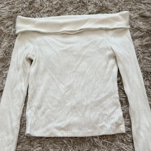 Vit ribbad offshoulder topp Stradivarius - Säljer en vit ribbad offshoulder topp från Stradivarius i storlek XS. Toppen har långa ärmar och en bred kant upptill som ger en snygg offshoulder-look. Materialet är mjukt och stretchigt, perfekt för att styla med jeans eller kjol. Supersnygg till alla dina outfits!
