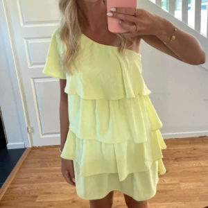 Gul one shoulder volangklänning - Säljer en ljusgul kortklänning med flera volanger och one shoulder-design. Väldigt eftertraktad och svår att få tag i, därav priset. Vid snabb affär går priset att diskutera 🥰 Bilden är tagen från Pinterest så inte min egna!!