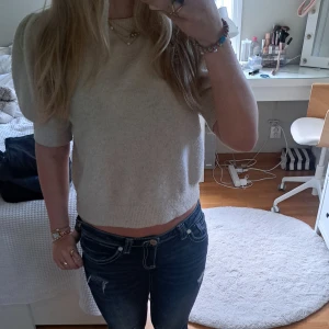 Beige stickad tröja Vero Moda - Säljer en beige stickad tröja från Vero Moda i storlek M. Tröjan har korta puffärmar och rund halsringning. Den har ribbade detaljer vid hals och nederkant. Perfekt att styla med jeans.