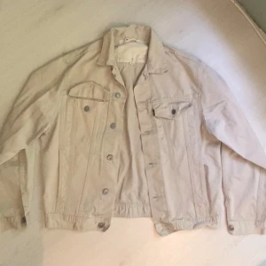 Beige jeansjacka  - Snygg beige jeansjacka med klassisk krage, knappar framtill och två bröstfickor med lock. Jackan har långa ärmar och detaljerade sömmar som ger en cool look. Perfekt att slänga på sig när du vill ha en stilren men vintage look. Storlek L men passar som M/S. Pris kan diskuteras. 