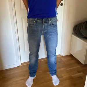 Blå jeans från Jack & Jones, strl 30/32 - Säljer ett par klassiska blå jeans från Jack & Jones, modell JJIMIKE JJFOX CB 056. Jeansen har fem fickor, normal passform och raka ben. Snygg ljusblå tvätt med subtila slitningar och kontrastsömmar. De är i perfekt skicka då de är aldrig använda. Nypris 599kr.