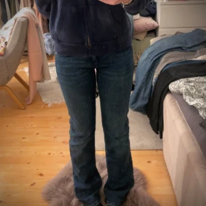 Gina tricot Blå bootcut jeans med låg midja - Säljer ett par blå jeans från Gina Tricot med snygg bootcut och låg midja. Jeansen har markerade sömmar, klassiska fickor med lock och silverfärgade knappar. Materialet är jeans med en mörk tvätt och coola detaljer som ger en trendig vibe. Jag är 165 och byxorna är nån centimeter lång men passar nog folk mellan 160-170