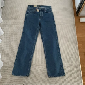 Nudie Jeans Tuff Tony Wavy Blues W28 L32 - Säljer ett par Nudie Jeans Tuff Tony Wavy Blues i klassisk blå denim. Modellen har raka ben, hög midja och snygga broderade bakfickor med vågmönster. Jeansen är tillverkade i 100% bomull och har Nudie Jeans logga på läderpatchen bak.