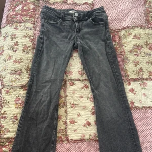 Grå bootcut jeans med fickdetaljer - Snygga grå lågmidjade jeans med bootcut passform och coola fickor med lock och knapp bak. Klassisk femficksdesign och knappgylf framtill. Jeansen har en mörkgrå tvätt och är tillverkade i jeansmaterial som ger en skön känsla. Det lilla märket sitter på baken och märks knappt när man har på sig. Vill bli av med såfort som möjligt så pris kan diskuteras💕