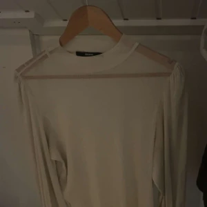 Glittrig beige långärmad topp Bik Bok - Säljer en beige långärmad topp från Bik Bok i storlek M. Toppen har glittrigt material och transparenta mesh-detaljer vid axlar och över bröstet. Perfekt för dig som gillar stilrena plagg med en twist. Snygg att matcha med jeans eller kjol.
