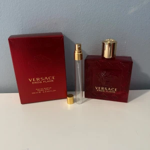 Versace Eros Flame Eau de Parfum - Versace Eros Flame Eau de Parfum 100 ml med lyxig röd flaska och gulddetaljer. Medföljande röd kartong och en liten refillflaska med guldfärgat lock. Flaskan har Versaces ikoniska Medusa-motiv och en elegant, fyrkantig form.