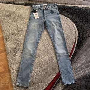 Slim fit ljusblå jeans Jack & Jones - Snygga ljusblå slim fit jeans från Jack & Jones, modell Glenn. Jeansen har klassisk femficksdesign, knappgylf och coola slitningar för en modern look. Perfekta för dig som gillar stilrena och trendiga jeans. De är helt nya märkte att de var för små och de är även oanvända. Vid fundering hör av er. Pris kan diskuteras vid snabb affär