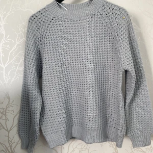 Ljusgrå stickad tröja från 157 - Säljer en ljusgrå stickad tröja från 157 i storlek M. Tröjan har ett grovt, luftigt stickat mönster och ribbade muddar vid hals, ärmslut och nederkant. Perfekt för dig som gillar chill och enkel stil. Passar dig som vill ha en basic men snygg tröja.