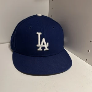 Blå LA Dodgers keps från New Era - Säljer en klassisk blå LA Dodgers 59FIFTY keps från New Era med vit broderad LA-logga framtill och MLB-logga bak. Kepsen har rak skärm och är tillverkad i 100% polyester. Köpt i london i en kepsbutik 