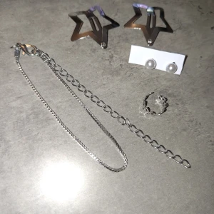 Smyckeset - Säljer ett smyckeset med stora stjärnformade hårspännen silverfärg, ett par klassiska pärlörhängen, en tunn silverfärgad semband och en söt ear cuff med fint mönster. Allt levereras i en transparent påse med vita stjärnor. Perfekt för dig som gillar att mixa olika stilar!