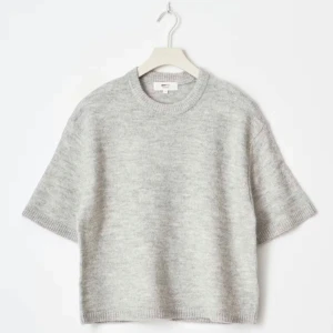 Grå stickad kortärmad tröja från Gina - Säljer en ljusgrå stickad tröja från gina med korta ärmar och rund hals. Tröjan har en loose passform och är perfekt för lager-på-lager. Mjuk och skön ullblandning som ger en chill vibe. Passar dig som gillar minimalistisk stil.