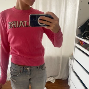Rosa stickad tröja Zadig & Voltaire - Snygg rosa stickad tröja från Zadig & Voltaire med broderad Z på ärmen och coolt texttryck framtill. Tröjan har rund hals, långa ärmar och ribbade muddar vid ärmslut och midja. Perfekt för dig som gillar färg och vill sticka ut lite extra.