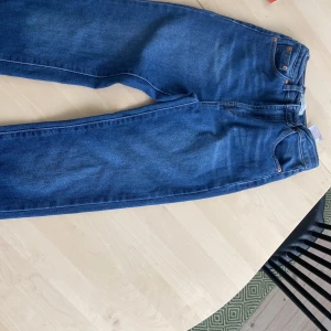 Levi's Ribcage Straight Ankle jeans blå - Säljer ett par Levi's Ribcage Straight Ankle jeans i klassisk blå färg. Modellen har hög midja och raka ben som slutar vid ankeln. Jeansen har fem fickor, kopparfärgade nitar och Levi's patch bak. Perfekt för dig som gillar retrovibe och clean look.
