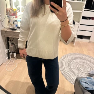 Vit stickad tröja med ribbade detaljer - Säljer en vit stickad tröja med rund hals och ribbade muddar vid ärmslut och nederkant. Tröjan har en loose passform och långa ärmar, perfekt för att chilla eller hänga med kompisar. Enkel och clean stil som funkar till jeans eller kjol.