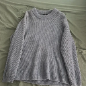 Grå stickad tröja från Lindex - Säljer en mysig grå stickad tröja från Lindex. Tröjan har en enkel design med långa ärmar och en rund halsringning. Perfekt för kyliga dagar.