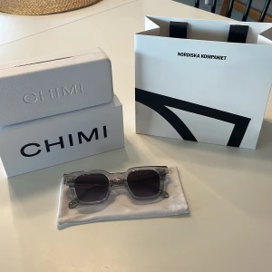 Gråa Solglasögon från CHIMI 04 - Snygga solglasögon från CHIMI med transparent grå båge och mörka fyrkantiga linser. Dessa är från NK i Göteborg. Stilren och modern design som passar perfekt till sommaren. Kommer i original fodral och NK påse. Modell:04. I helt nytt skick. Original pris: 1250kr.
