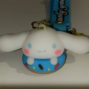 Cinnamoroll nyckelring med blå donut - Supergullig nyckelring med Cinnamoroll-figur som sitter i en blå donut med strössel. Nyckelringen har även en liten muffin-berlock och ett blått band med texten 'only you'. Perfekt som accessoar till väskan eller nycklarna! Helt oanvänd