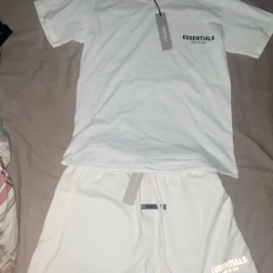 Vita shorts från Essentials Fear of God - Snyggt och enkelt set från Essentials Fear of God i vit färg. Setet består av: 	•	Vit t-shirt med liten logga på bröstet 	•	Vita shorts med logga på benet och gummimärke vid midjan  Plaggen är aldrig använda och har fortfarande taggen kvar. Väldigt sköna och passar till en stilren streetwear-look.  100 % äkta. Perfekt för dig som gillar Fear of God och enkel stil.  Storlek S på båda Shortsen passar som S och M  Skriv gärna om du har frågor eller vill köpa båda tillsammans! 