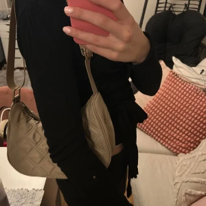 Beige axelväska - Säljer en beige axelväska med quiltat mönster och justerbar rem. Väskan har dragkedja upptill och ett innerfack med dragkedja. Perfekt storlek för det viktigaste, man får plats med mer än man tror, både telefon, vattenflaska och leggings samtidigt! Pris kan diskuteras och skriv för fler bilder💕