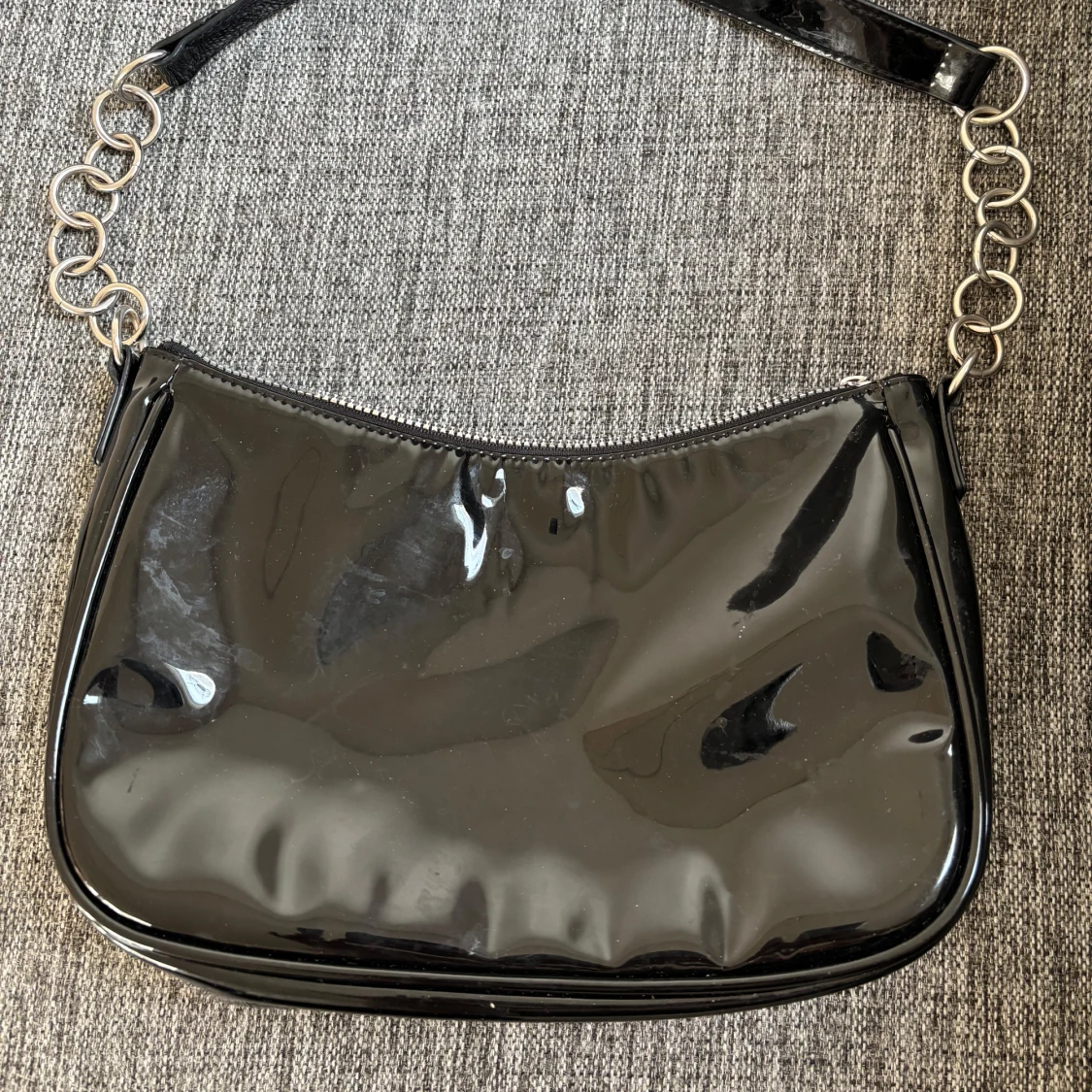 Svart axelväska med kedjedetaljer. Material:lack.   - 1