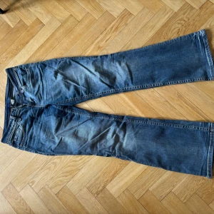 Blå lågmidjade bootcut jeans - Snygga blå jeans från H&M Divided med femficksdesign. En knapp där bak har åkt av men går lätt att sy på. De är väldigt sköna, inte sånt typiskt jeans material. 