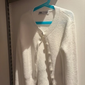 Vit kofta från Zara - Säljer en stilren vit kofta från Zara med knappar framtill. Koftan är använd en gång.